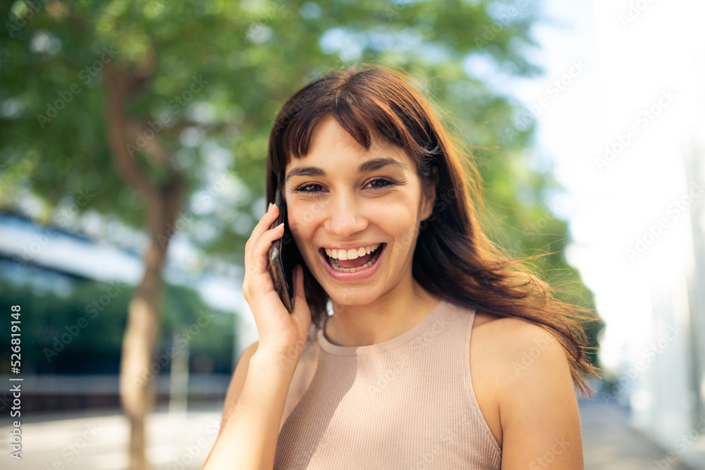 Cheerful young woman talking on mobile phone in city Cheerful young woman talking on mobile phone in city