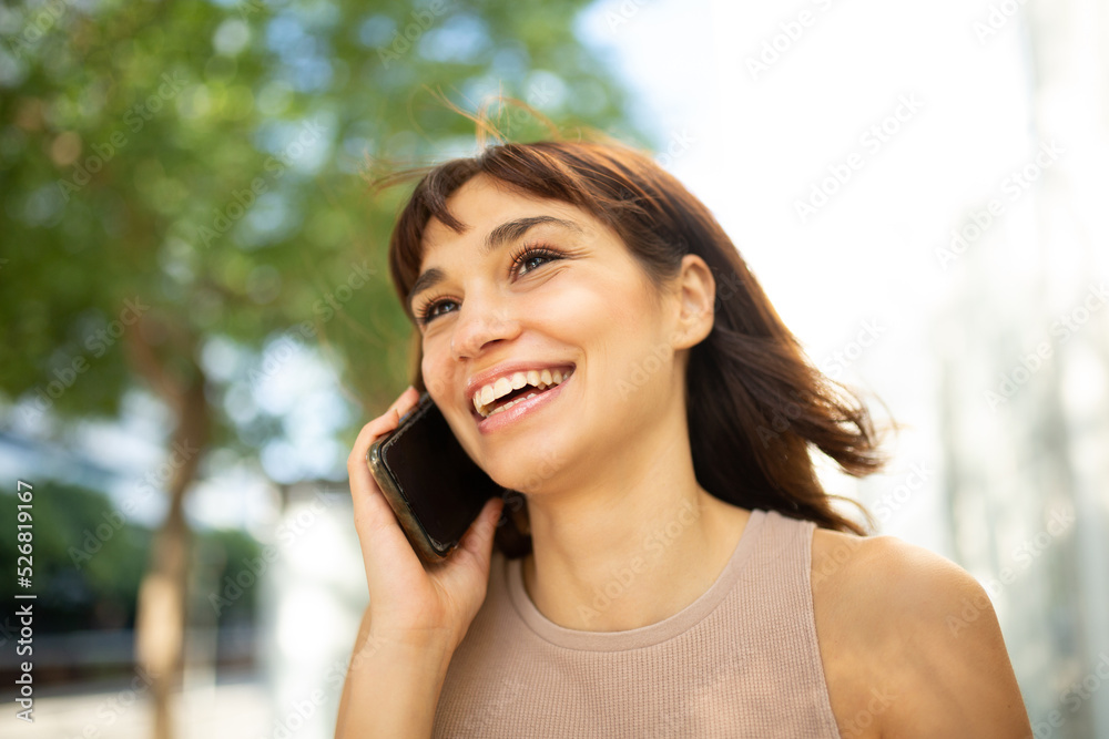 Beautiful young woman talking on cellphone in city