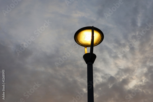 Glowing led lamp on background of evening sky with dark clouds. Electric lighting, energy-saving street lantern