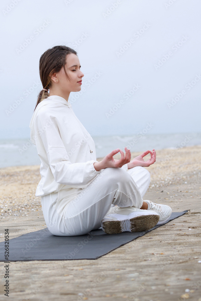 Vertical photo of young girl sitting on the yoga mat doing meditation