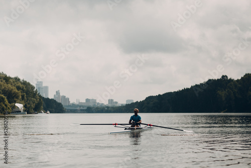 Sportsman single scull man rower rowing on boat.