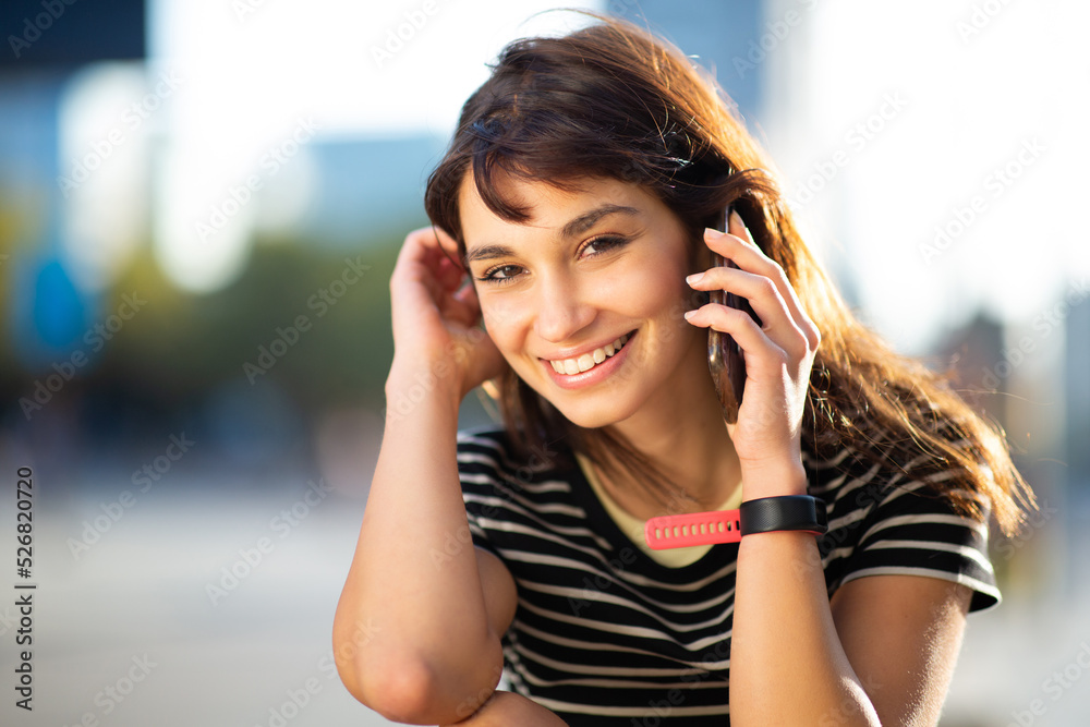 Beautiful young woman talking on mobile phone sitting outside Beautiful young woman talking on mobile phone sitting outside