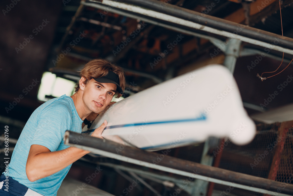 Sportsman single scull man rower sportsman checking carbon surface of boat. Sportsman single scull man rower sportsman checking carbon surface of boat.