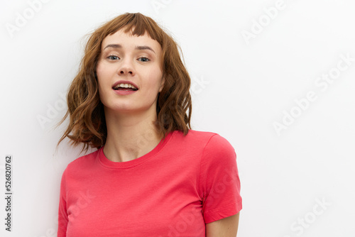 a sweet, happy, charming woman with red hair and a beautiful wide smile stands on a white background in a red T-shirt