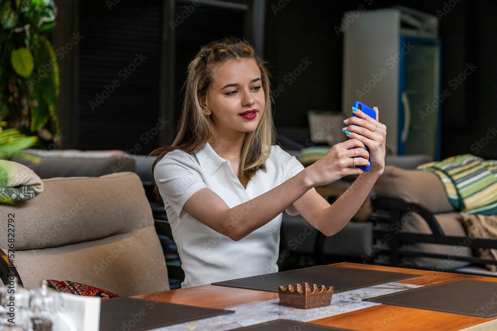 Young lady sitting at the restaurant and taking selfie Young lady sitting at the restaurant and taking selfie