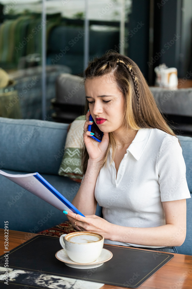 Serious lady talking on the phone and looking at the notebook Serious lady talking on the phone and looking at the notebook