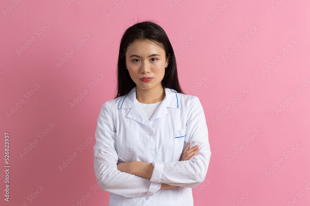 Asian positive doctor woman in white medical gown against pink background portrait Asian positive doctor woman in white medical gown against pink background portrait