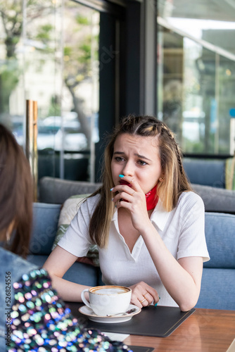 Vertical photo of young lady sitting at the cafe and talking with her friend