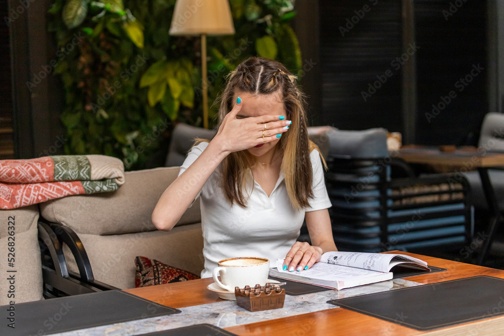 Beautiful lady sitting at the restaurant and holding her hand her eyes Beautiful lady sitting at the restaurant and holding her hand her eyes