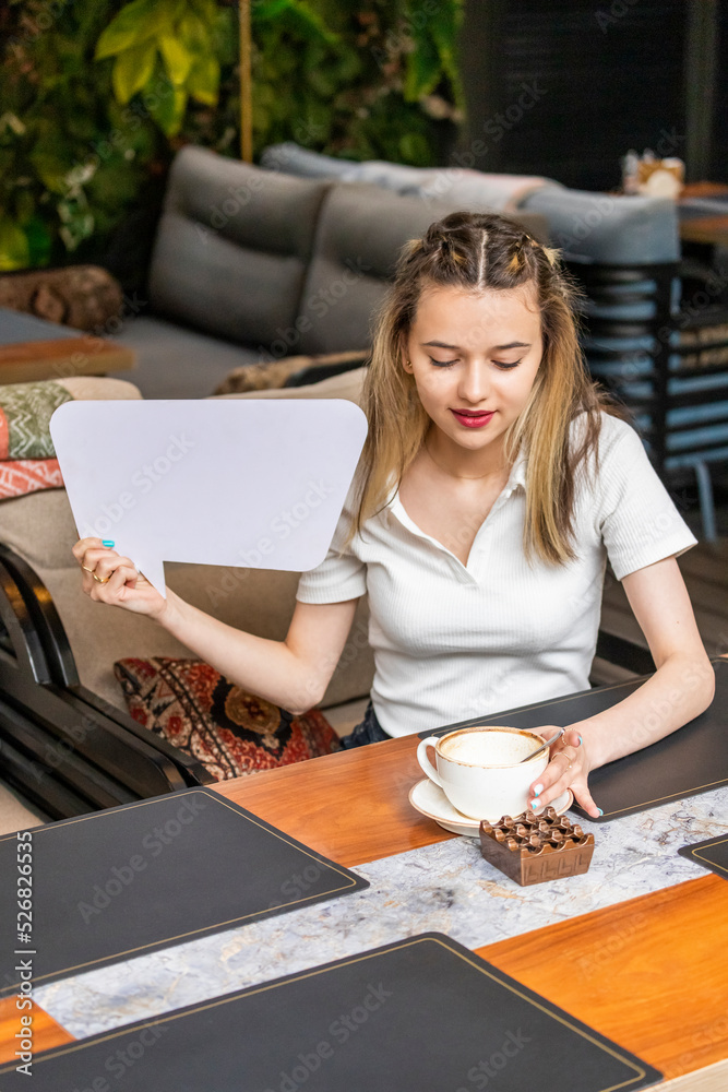 Vertical photo of young lady holding white idea board and looking at her coffee Vertical photo of young lady holding white idea board and looking at her coffee