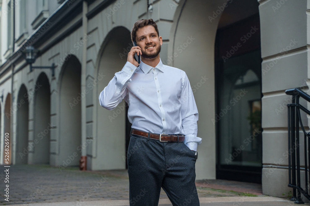 Portrait of businessperson dressed in white shirt talking on cellphone outdoors in city street. Portrait of businessperson dressed in white shirt talking on cellphone outdoors in city street.