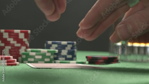 Poker player with a tattoo checking his hand, having a pair of jacks.