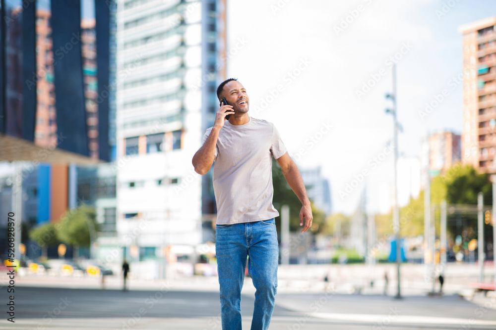Man looking up while talking on mobile phone outdoors in city