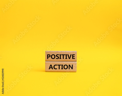 Positive action symbol. Concept words Positive action on wooden blocks. Beautiful yellow background. Business and Positive action concept. Copy space.
