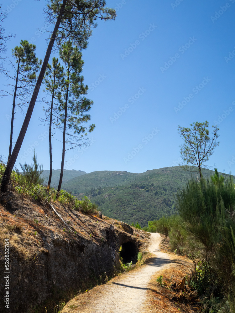 PR10 SEI walking route aside a water channel separating the pine trees forest below and the rocky mountain above in Serra da Estrela, Portugal PR10 SEI walking route aside a water channel separating the pine trees forest below and the rocky mountain above in Serra da Estrela, Portugal