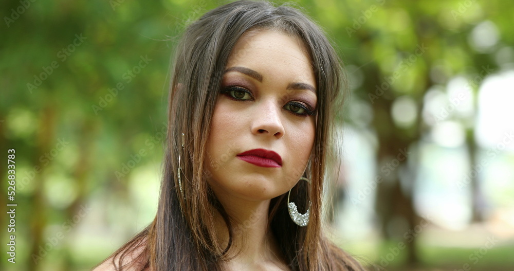 Hispanic millennial girl headshot outside in nature looking to camera. Young woman portrait face Hispanic millennial girl headshot outside in nature looking to camera. Young woman portrait face