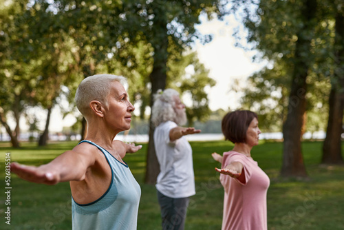 Woman with blurred friends practicing yoga on lawn