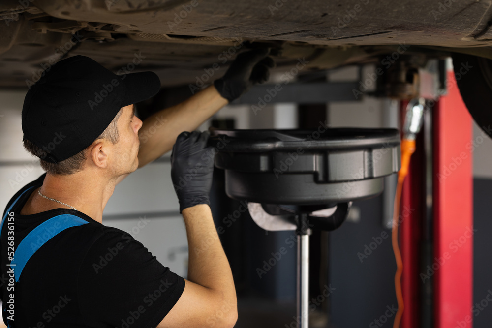 Mechanic drain the old oil from the engine through the drain plug