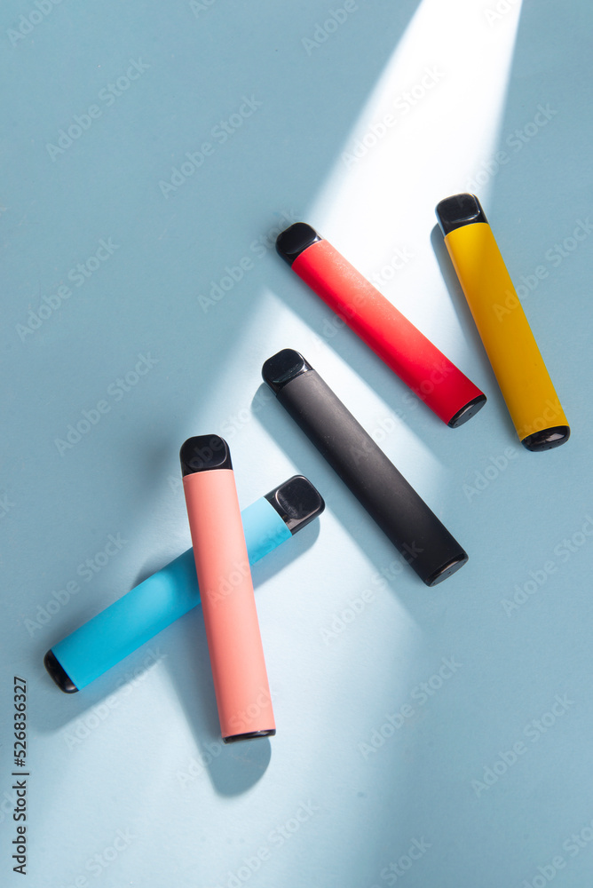 Set of colorful disposable electronic cigarettes on a blue background with hard light. The concept of modern smoking. Top view Set of colorful disposable electronic cigarettes on a blue background with hard light. The concept of modern smoking. Top view