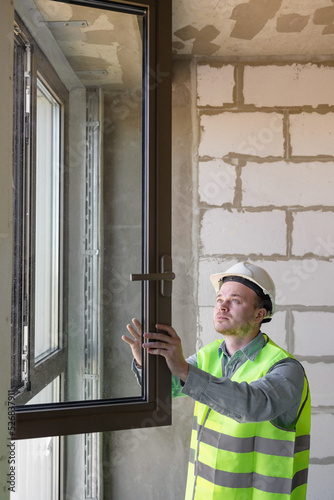 male chief engineer in the room make measurements of windows, specialists in the installation and replacement of double-glazed windows. measurement of heat loss. engineer, a man in white helmets and