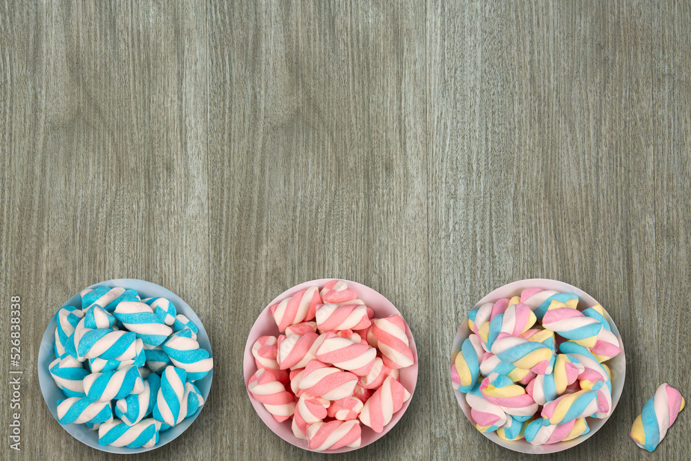 Three pots with colorful marshmallows on wooden background