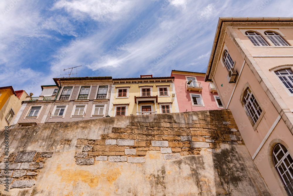 Fototapeta premium View from below of the houses and facades of the city walls of the old university city of Coimbra, Portugal