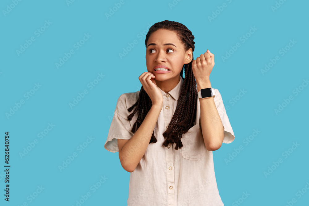 Displeased impatient woman pointing finger on her wrist clock, looking at camera with anxious, worried about deadline, wearing white shirt. Indoor studio shot isolated on blue background. Displeased impatient woman pointing finger on her wrist clock, looking at camera with anxious, worried about deadline, wearing white shirt. Indoor studio shot isolated on blue background.