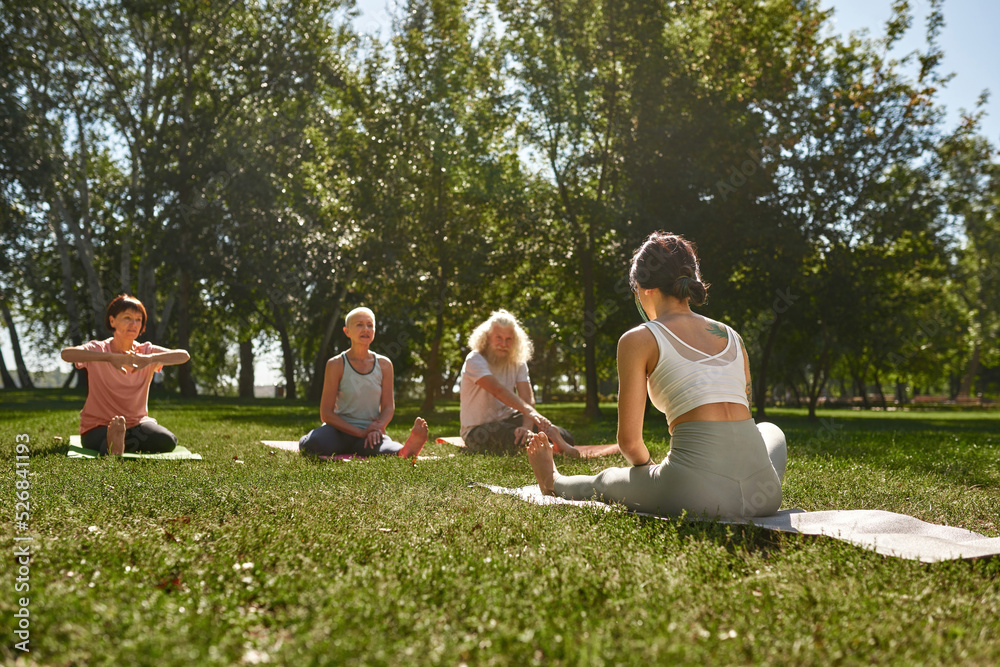 Back of woman teach mature people practicing yoga Back of woman teach mature people practicing yoga