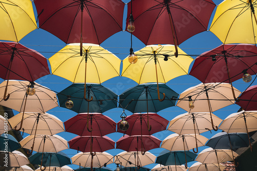 colorful umbrellas and Edison light bulbs hanging out above a city street
