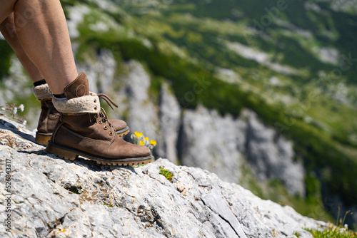 closeup of Caucasian woman legs with hiking brown leather boots on mountain rock