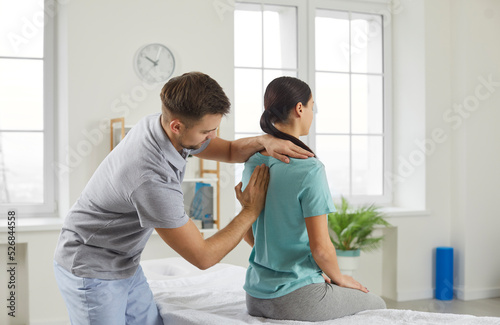 Male chiropractor, physiotherapist or osteopathy specialist examining a female patient with scoliosis or back ache. Physiotherapy, modern orthopaedic therapy, scoliosis treatment concept photo