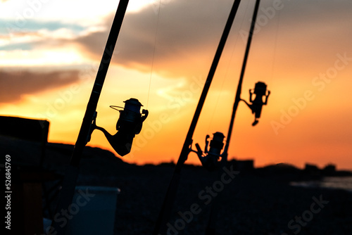 Silhouette of fishing rod with reels at sunset. Fishing equipment.