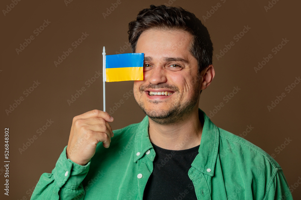 Stylish man in green shirt with Ukrainian flag on brown background Stylish man in green shirt with Ukrainian flag on brown background