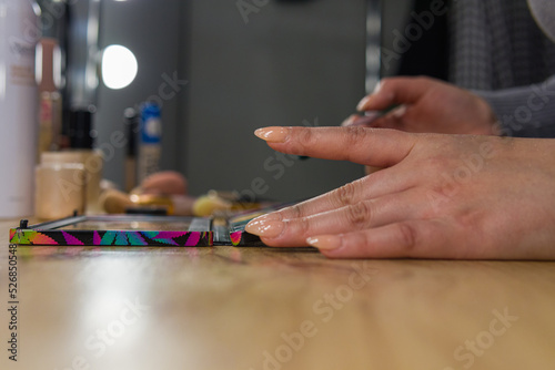 close-up shot of the right hand fingers of a woman in action surrounded by makeup stuffs