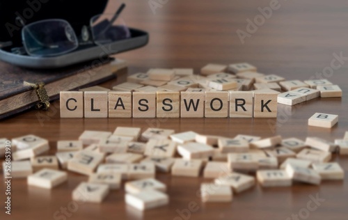 classwork word or concept represented by wooden letter tiles on a wooden table with glasses and a book