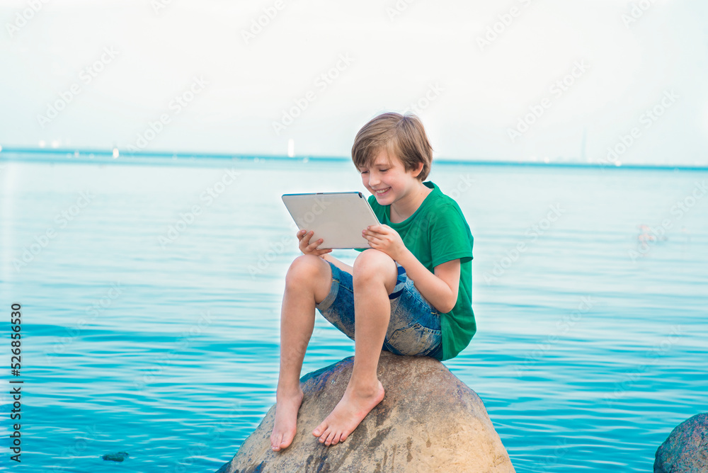 happy boy travels and vacations in different countries, studies online at the sea