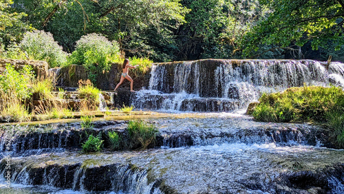 une fillette en maillot de bain au milieu d'une cascade