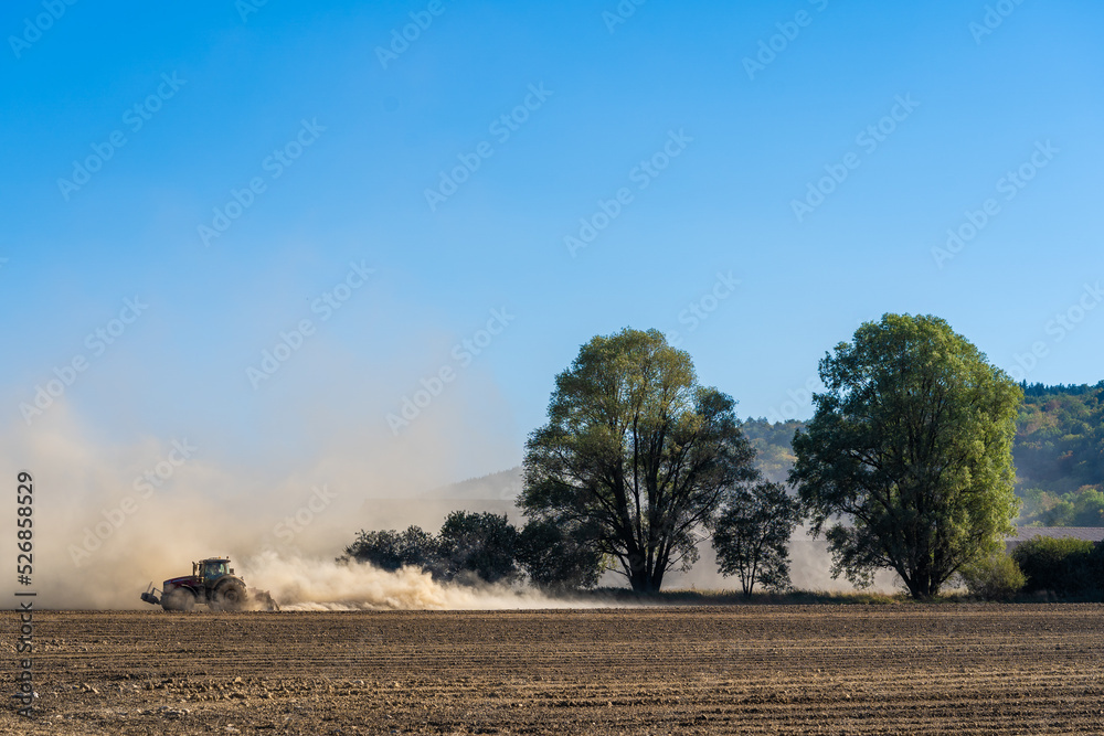 un tracteur laboure la terre asséchée d'un champ
