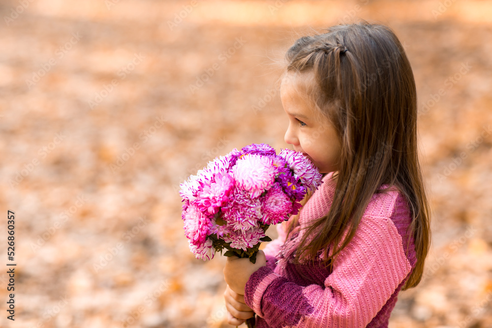 Cute little girl in autumn park with pink flower bouquet. Cute little girl in autumn park with pink flower bouquet.