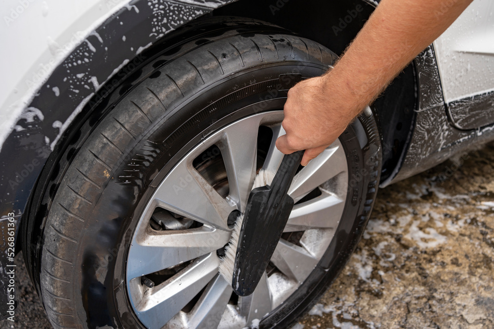 brush cleaning a car's rims