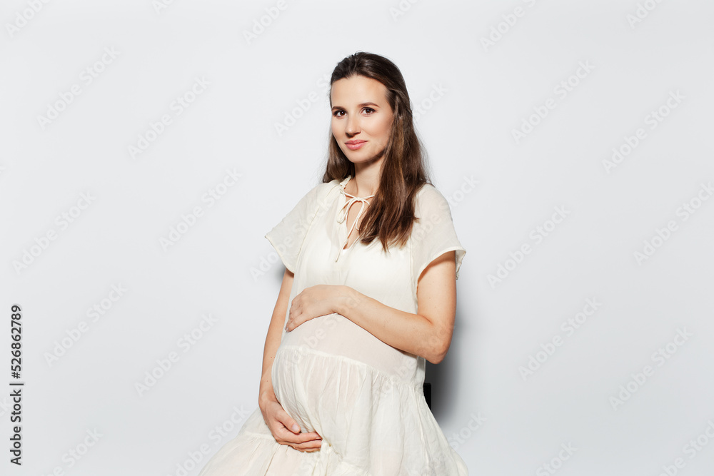 Studio portrait of young pregnant woman touching the belly on white background. Studio portrait of young pregnant woman touching the belly on white background.