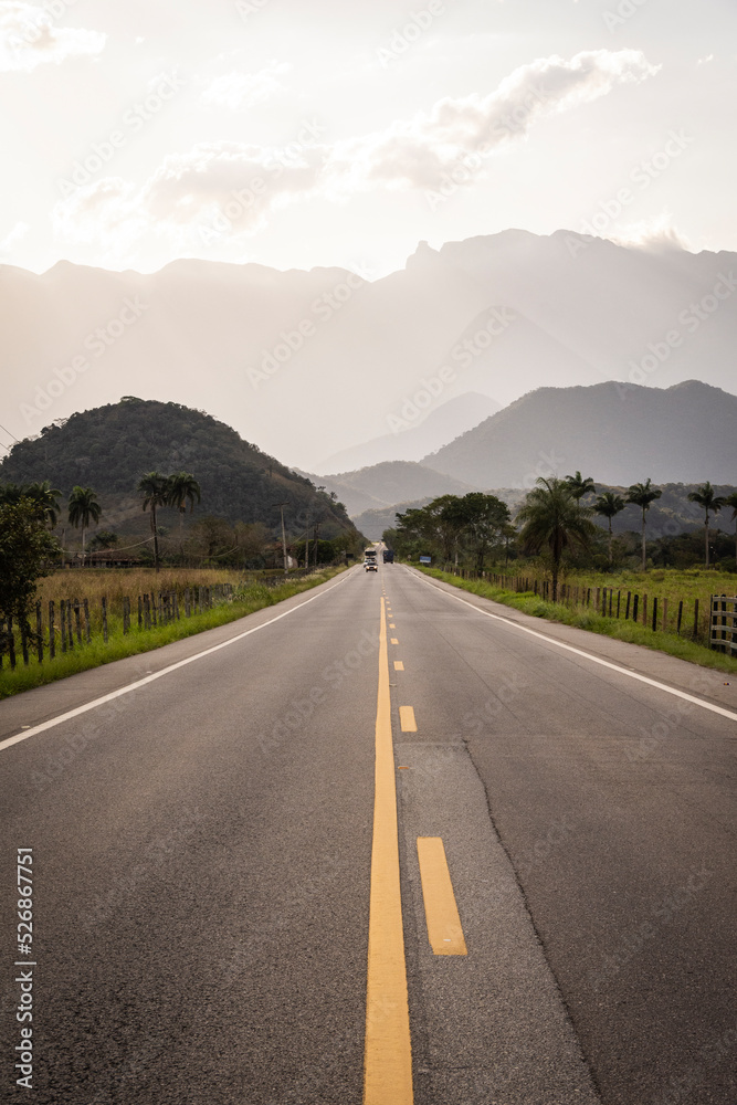 Naklejka premium Beautiful coutryside road leading towards wall of high mountains