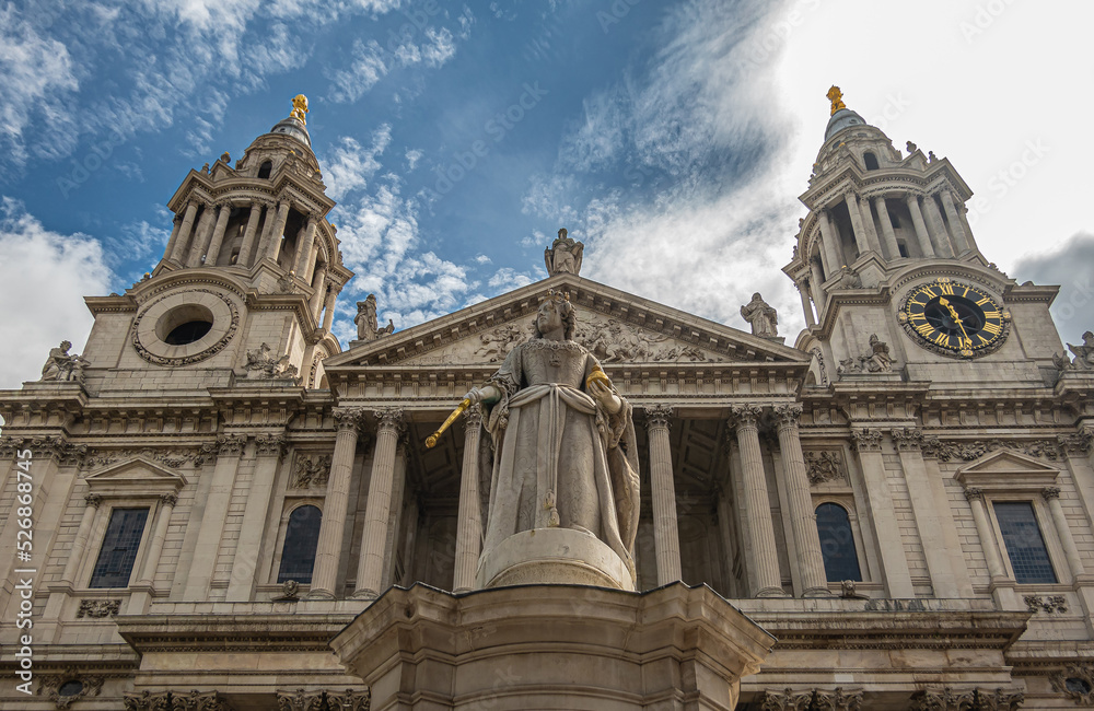 London, England, UK - July 6, 2022: St. Paul's Cathedral. Statue of Queen Anne on West churchyard with the 2 towers and facade pediment in back under blue cloudscape.