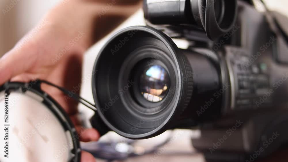 Hand taking a big video camera and a blue laptop on desk Hand taking a big video camera and a blue laptop on desk