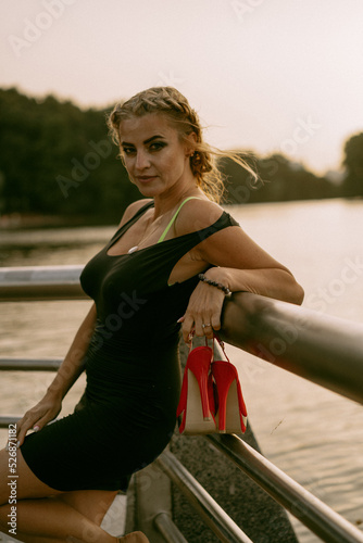 Beautiful mature woman with shoes in her hands walks in the park. © Yuliya Kirayonak