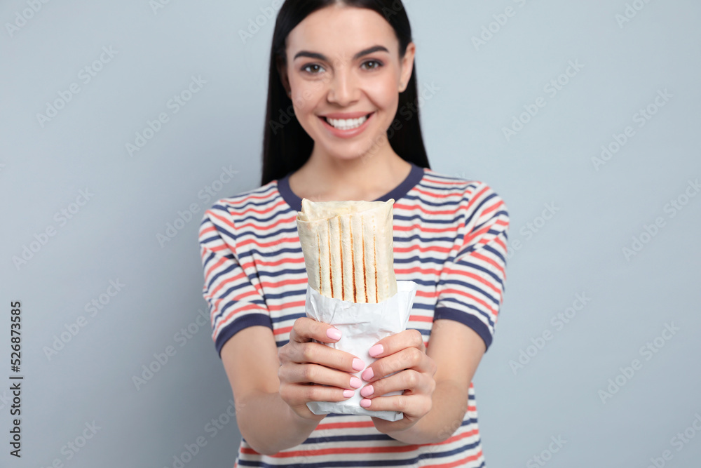 Happy young woman with delicious shawarma on grey background Happy young woman with delicious shawarma on grey background