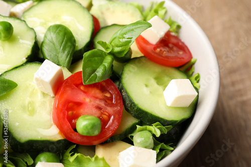 Tasty fresh salad with cucumber in bowl on table, closeup