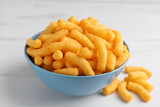 Many tasty cheesy corn puffs on white marble table