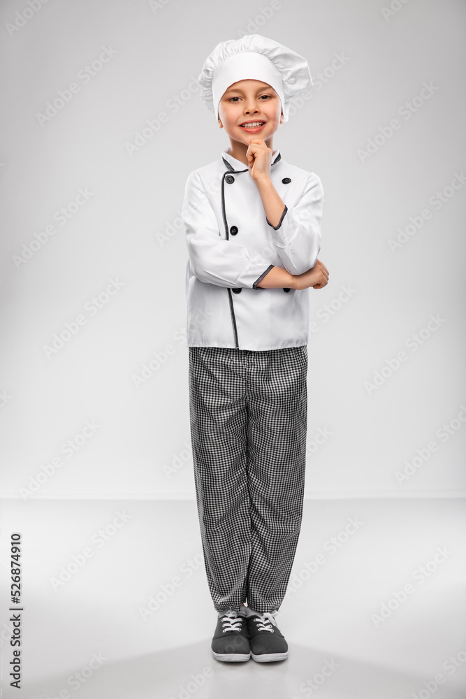 cooking, culinary and profession concept - happy smiling little boy in chef's toque and jacket over grey background cooking, culinary and profession concept - happy smiling little boy in chef's toque and jacket over grey background