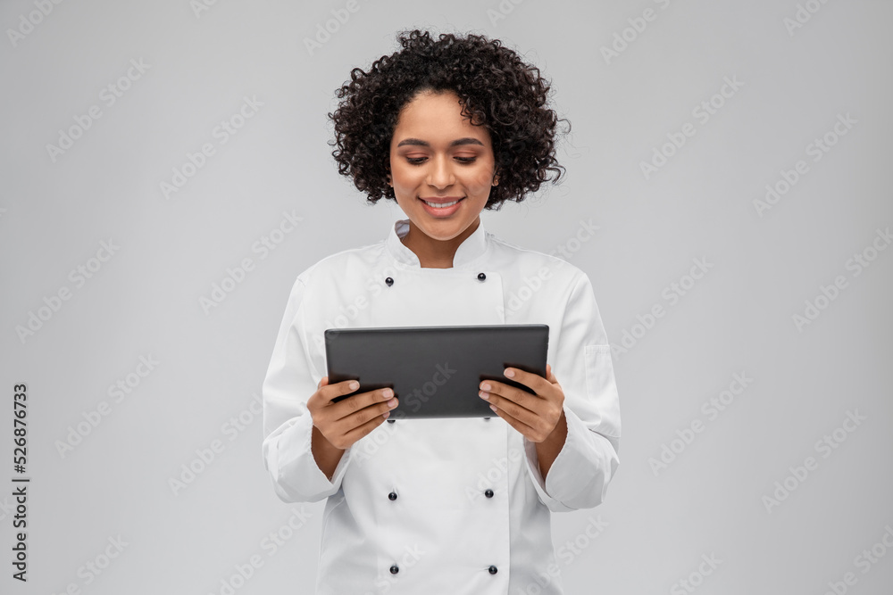 cooking, culinary and people concept - happy smiling female chef in white jacket with tablet pc computer over grey background cooking, culinary and people concept - happy smiling female chef in white jacket with tablet pc computer over grey background